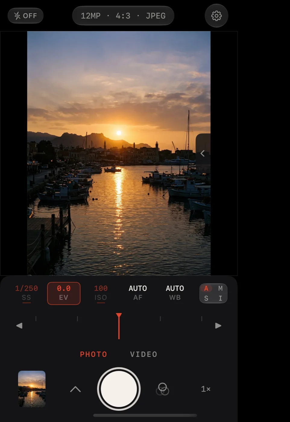 Lucid Camera on iPhone Duo closed outer display showing a harbor at sunset in the viewfinder above the compact deck in auto mode